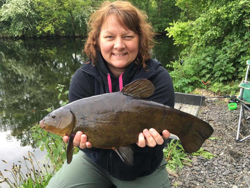 woman proudly holding a tench caught in on of our pools